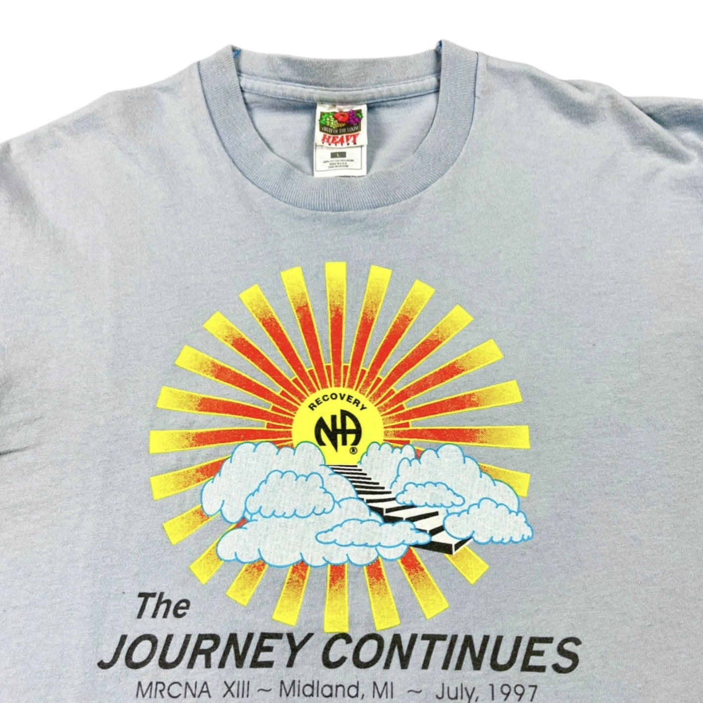 Gray t-shirt with a colorful graphic design featuring a sun, clouds, and text on a white background.